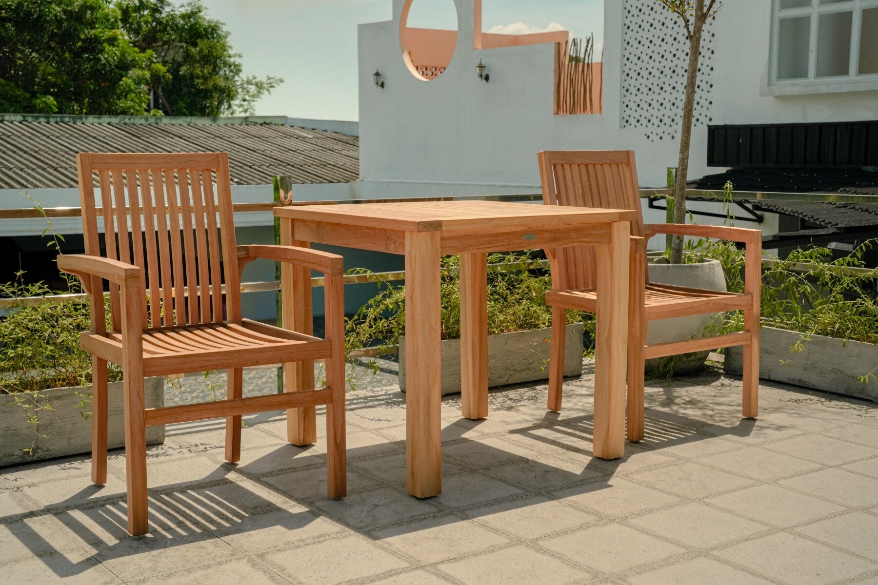 Moderne teakhouten tuinset met twee stapelbare Pile stoelen aan een vierkante, vaste tuintafel, stijlvol opgesteld op een terras.