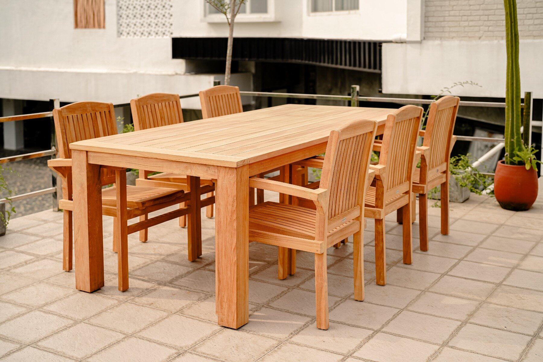 Een elegante Nelson teak tuintafel van 220x100 cm, gemaakt van hoogwaardig teakhout. De tafel heeft een strakke, moderne uitstraling met een natuurlijke houtnerf en een warme, gouden tint. Het stevige tafelblad biedt voldoende ruimte voor buitenmaaltijden