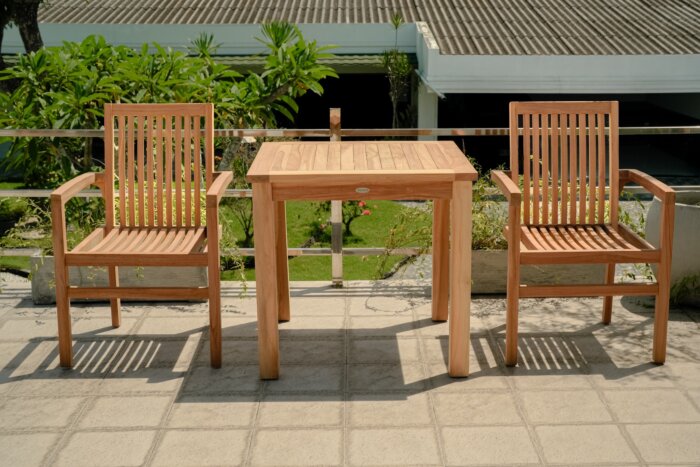 Moderne teakhouten tuinset met twee stapelbare Pile stoelen aan een vierkante, vaste tuintafel, stijlvol opgesteld op een terras.