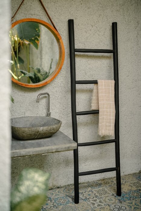 Een matzwarte houten decoratieladder, 175 cm hoog, 50 cm breed en 5 cm diep. De ladder heeft meerdere sporten met gelijkmatige tussenruimtes en staat licht hellend voor stabiliteit. De afwerking is glad en egaal, wat het minimalistische design benadrukt. 