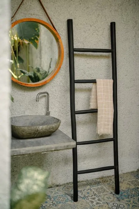 Een matzwarte houten decoratieladder, 175 cm hoog, 50 cm breed en 5 cm diep. De ladder heeft meerdere sporten met gelijkmatige tussenruimtes en staat licht hellend voor stabiliteit. De afwerking is glad en egaal, wat het minimalistische design benadrukt. 
