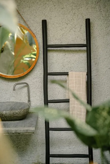 Een matzwarte houten decoratieladder, 175 cm hoog, 50 cm breed en 5 cm diep. De ladder heeft meerdere sporten met gelijkmatige tussenruimtes en staat licht hellend voor stabiliteit. De afwerking is glad en egaal, wat het minimalistische design benadrukt. 