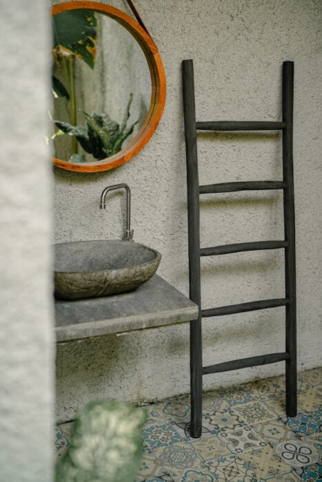 Een matzwarte houten decoratieladder, 150 cm hoog, 50 cm breed en 5 cm diep. De ladder heeft meerdere sporten met gelijkmatige tussenruimtes en staat licht hellend voor stabiliteit. De afwerking is glad en egaal, wat het minimalistische design benadrukt.