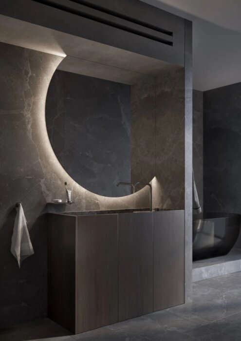 De VENUS spiegel is een moderne tweedelige ronde designspiegel met een unieke afwerking aan de bovenzijde en rechterzijde, ontworpen voor luxe woon- en sanitaire ruimtes. Verkrijgbaar in diverse maten (1200 mm - 2000 mm), met indirecte verlichting voor ee