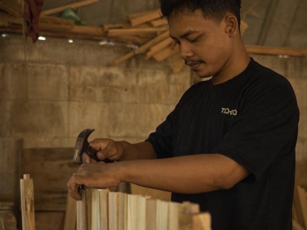 Tka home maker java - Teakea Meubelmaker Dika werkt met een hamer aan een houten frame in de werkplaats op Java